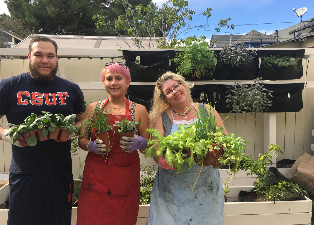 Our CSUF students holding up crops at the Pathways of Hope garden.